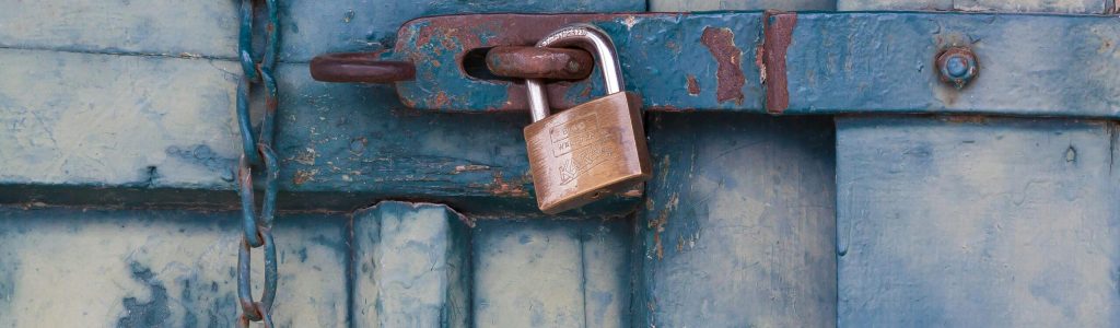 pexels-photo-164425-164425 A close-up of a rusty padlock securing a blue painted wooden door with chain and bolt.